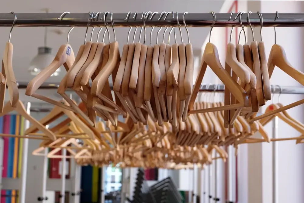 A rail of wooden coat hangers in a retail clothing shop.